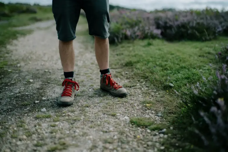 Walker in boots on a gravel trail through open countryside